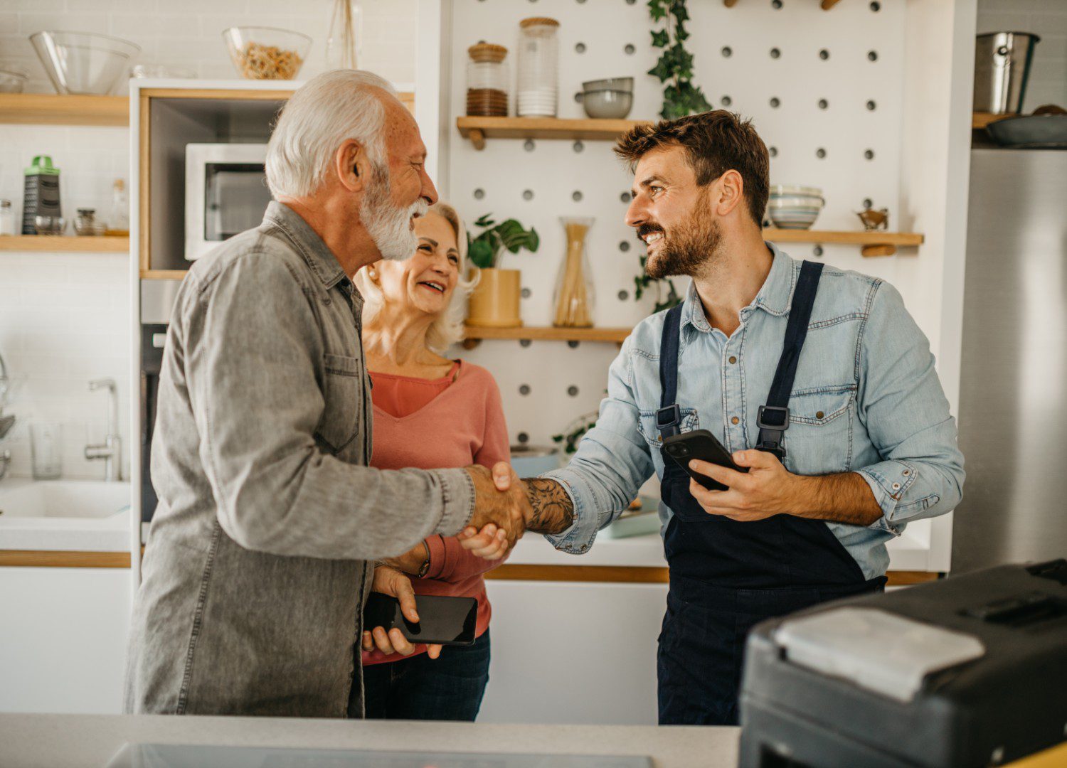 Older couple greeting young man in kitchen.