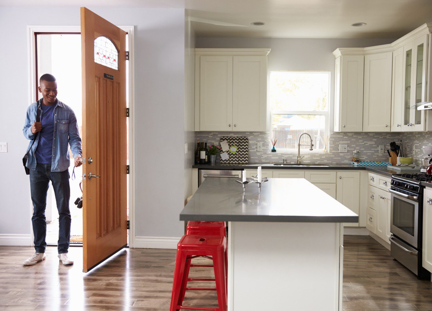 Man entering modern kitchen with open door.