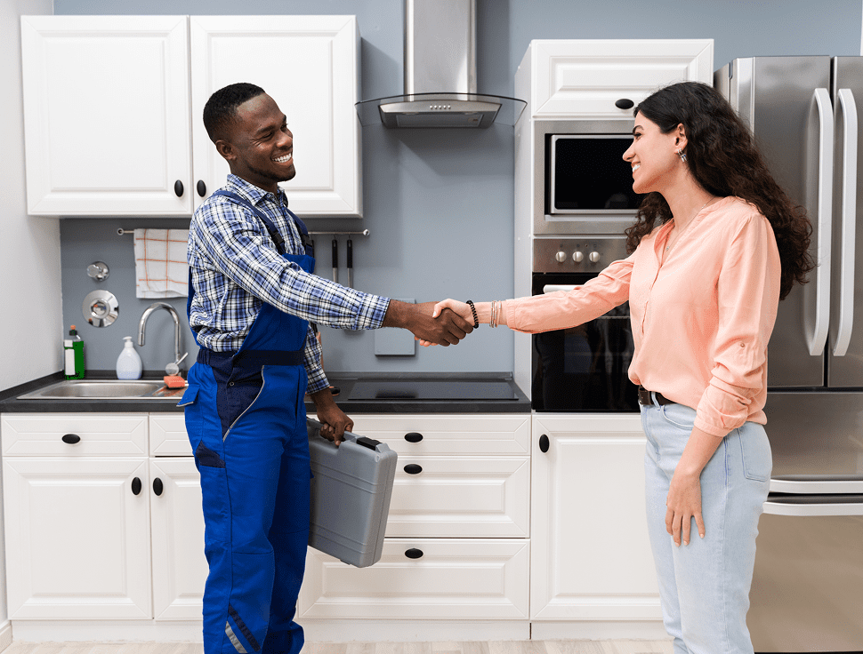 Technician and woman shaking hands in kitchen.